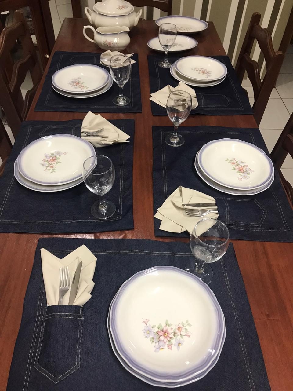 Mesa com jogos americanos em tecido escuro e louça clássica