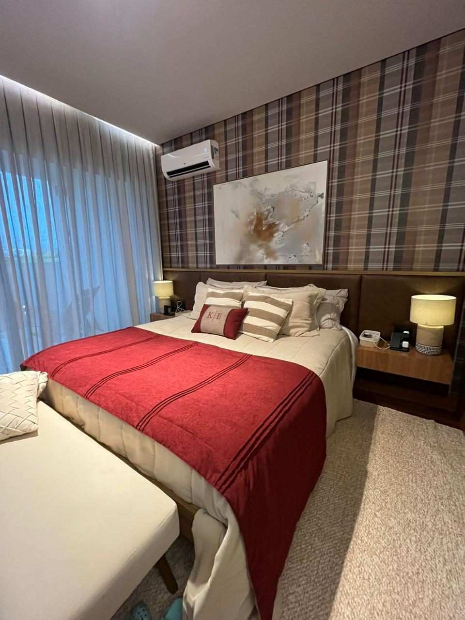 Quarto com cama arrumada e almofadas bordadas
